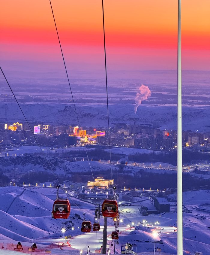 Red cable cars over a sunset-lit ski resort
