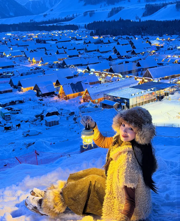 Traveller with a lantern outside the warm wooden cabins of Hemu at blue hour